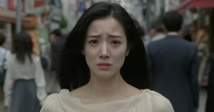 不安そうな表情の女性が雑踏の中で立ち尽くしている様子