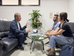 オフィスで国際的な探偵業について話し合う日本人探偵と外国人専門家