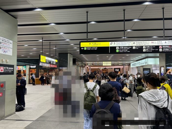 大阪駅構内で尾行中の調査員の視点。人混みの中でストーカー対象者を確認している様子。