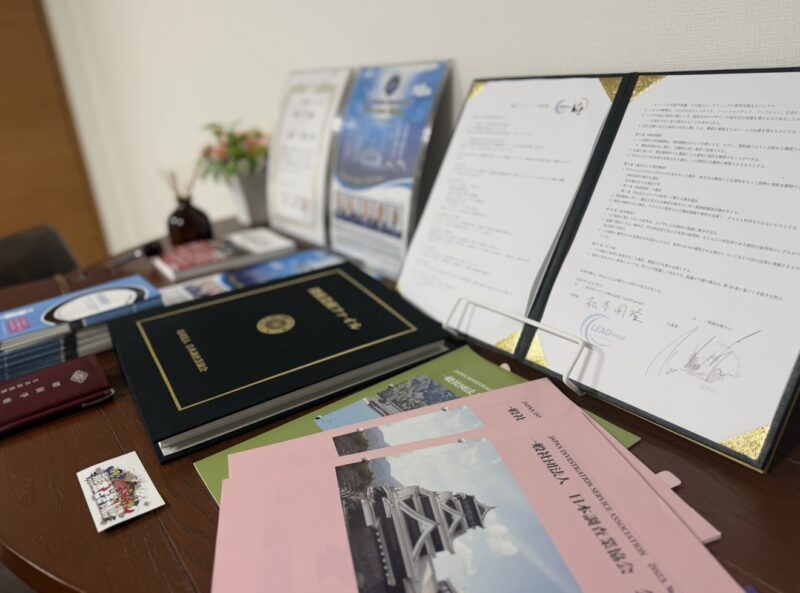 西日本リサーチ株式会社の相談室に並ぶ調査報告書、契約書類、会員証、業界資料の写真