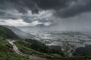 阿蘇の高台から見た豪雨の景色。黒い雲と激しい雨が広がる梅雨時期の自然風景