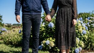 梅雨の時期に紫陽花の前で手をつなぐ男女の後ろ姿をイメージした不倫・浮気調査向け写真